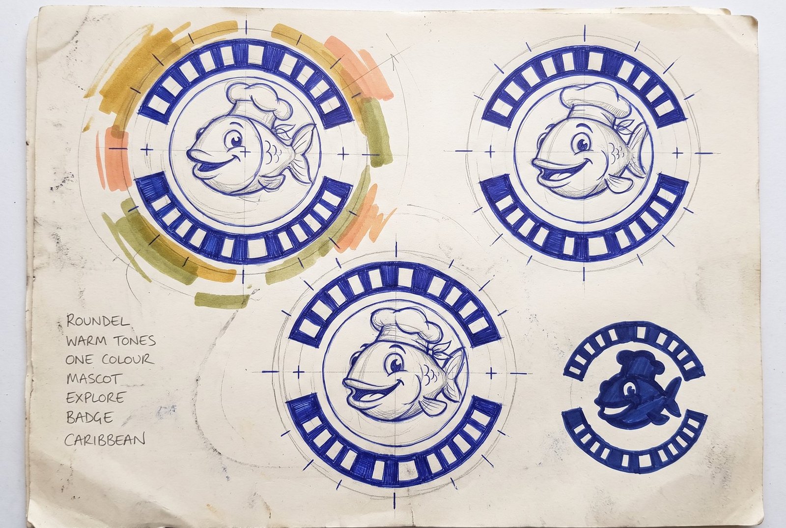 Concept sketch sheet: circular mascot badge studies with a cartoon fish-head character inside construction circles, ring lettering blocked in as solid shapes, and a one-colour silhouette study