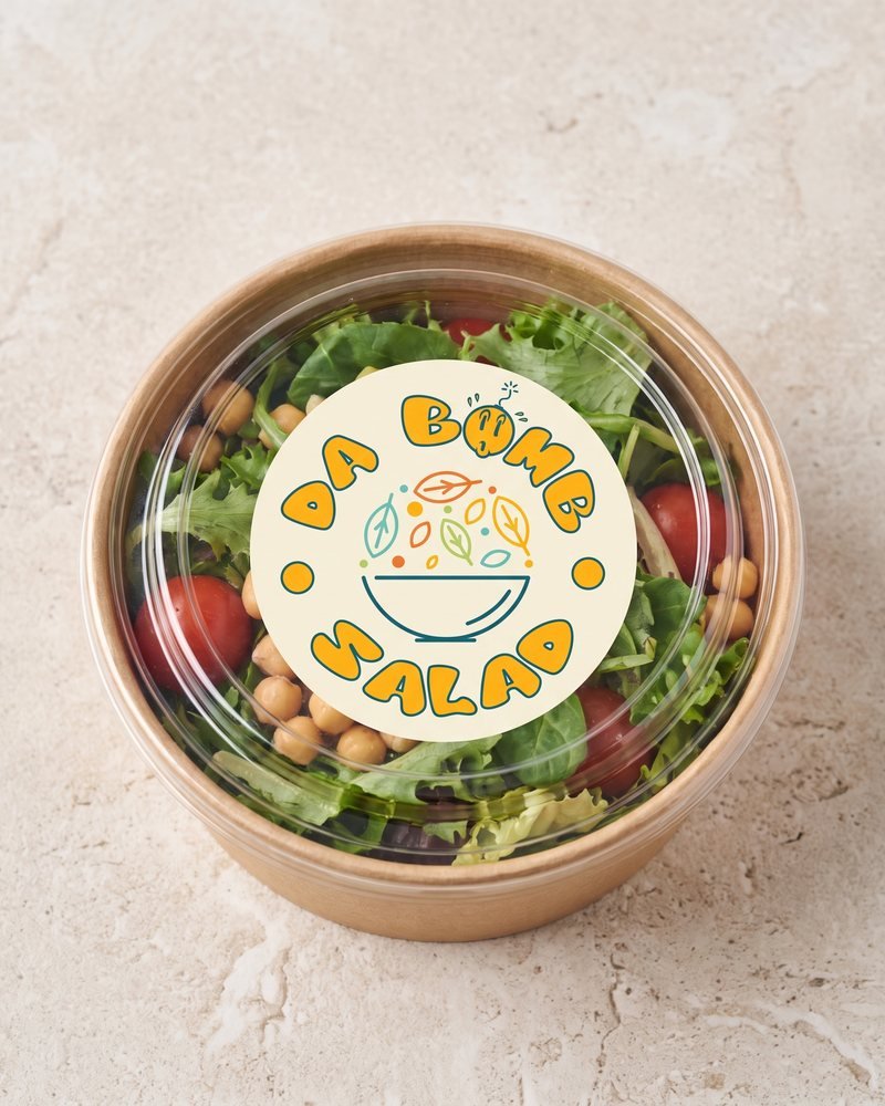 Mockup of the Da Bomb Salad logo on the lid label of a takeaway salad bowl