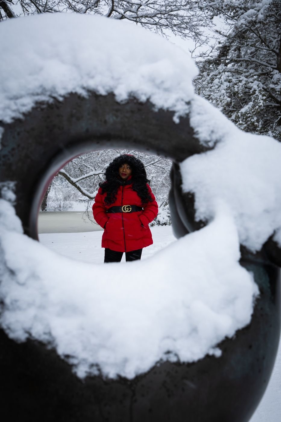 Woman in a red coat framed through a snow-covered sculpture
