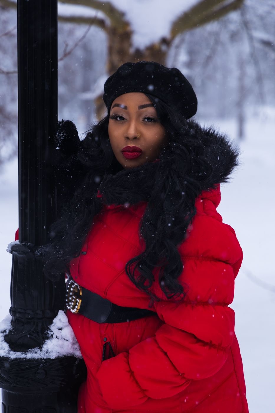Winter portrait of a woman in a red puffer coat and black beret in the snow