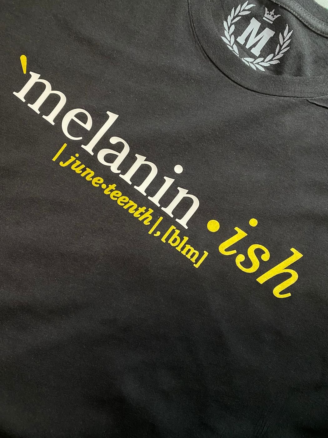 Close-up of the yellow Melanin-ish chest print on a black tee
