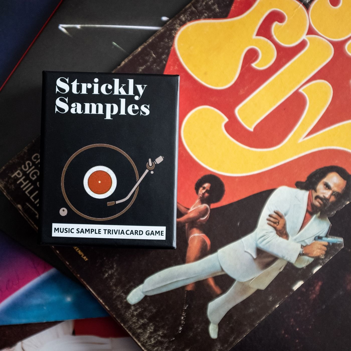 Strickly Samples card game box resting on vintage vinyl record sleeves
