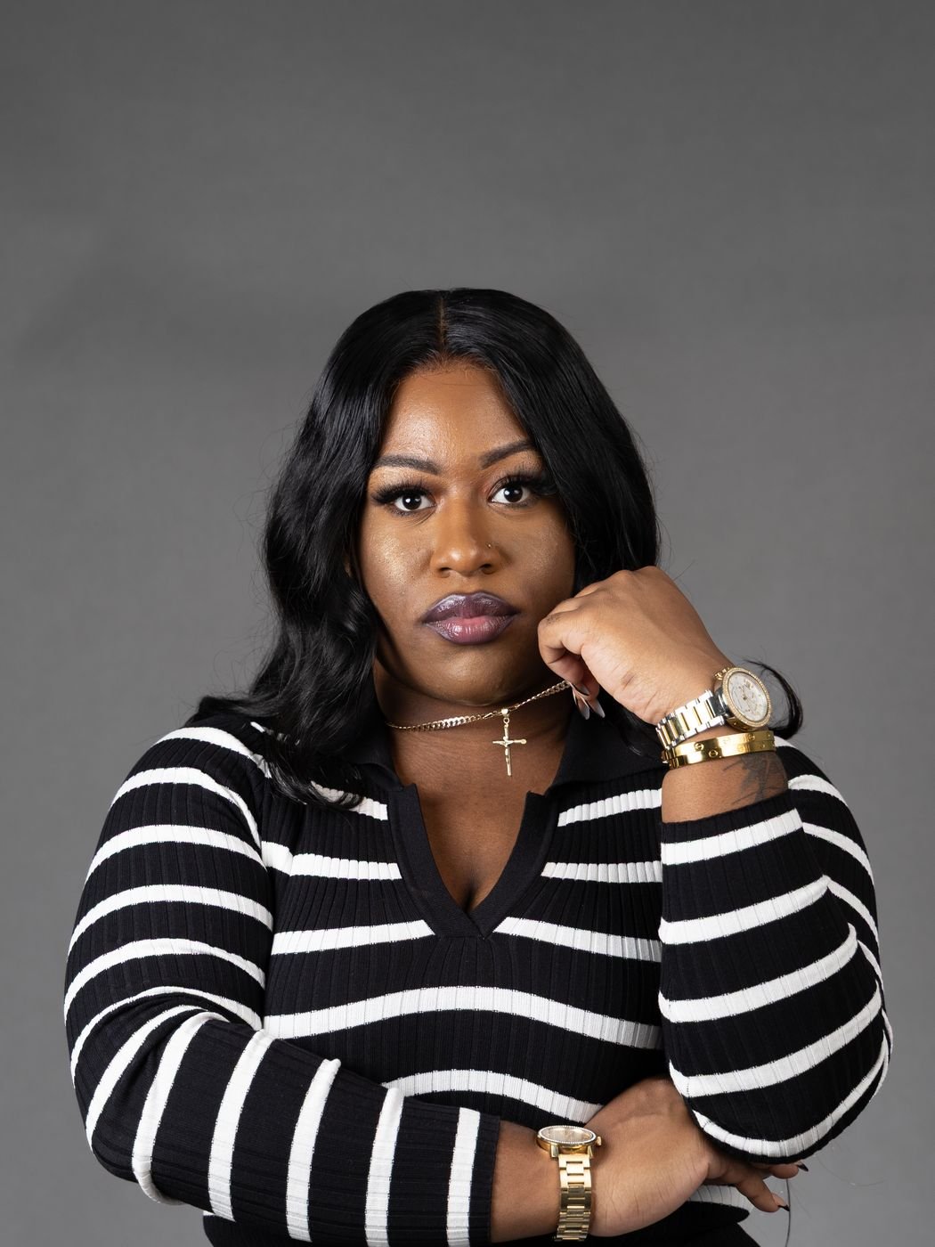Professional portrait in a striped sweater with a gold watch, grey backdrop