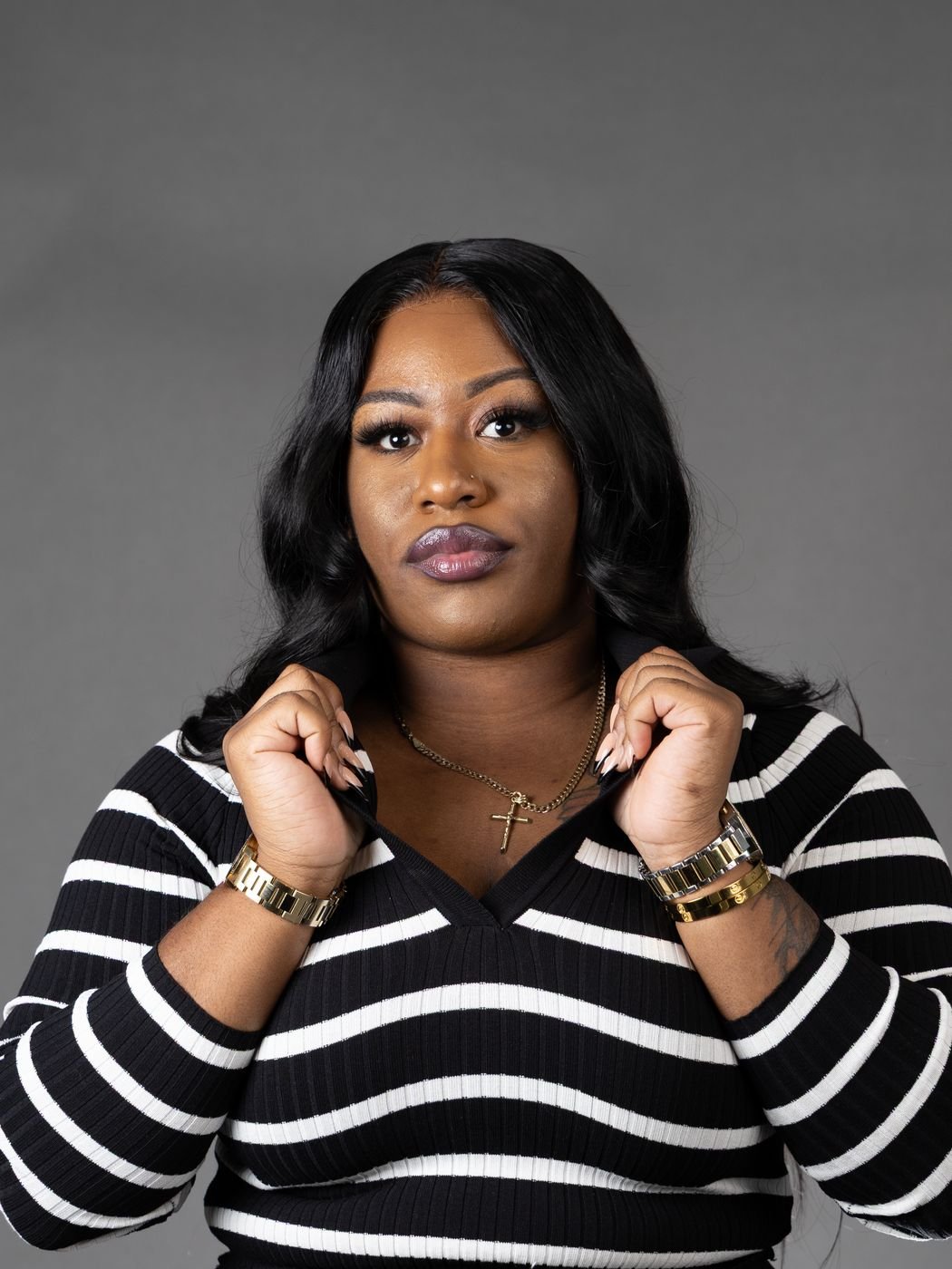 Studio headshot in a black and white striped sweater on a grey backdrop